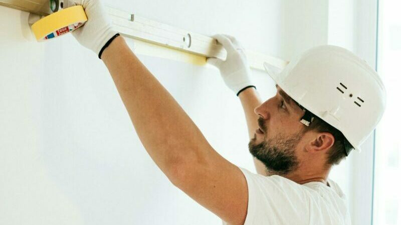 A construction worker using a spirit level to ensure accuracy on a wall installation.